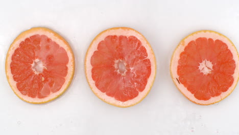 Superzeitlupenaufnahme-Von-Spritzendem-Wasser-Bis-Hin-Zu-Grapefruitscheiben,-Blick-Von-Oben